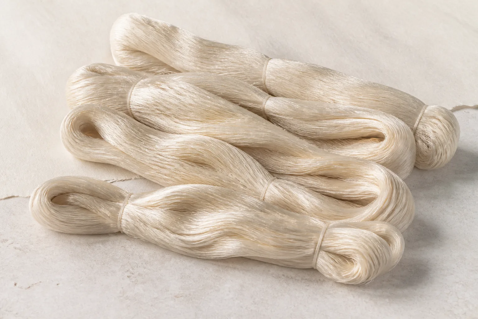 Representative undyed raw silk yarn arranged in elongated skeins on a neutral surface